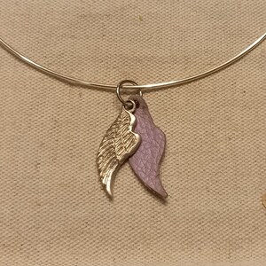 May include: A silver bangle bracelet with a gold and purple angel wing charm.