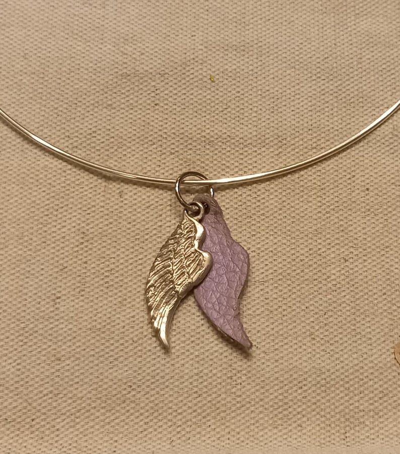 May include: A silver bangle bracelet with a gold and purple angel wing charm.
