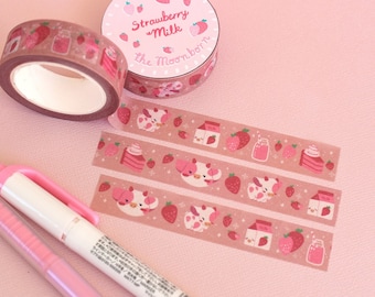 May include: Three rolls of pink and white patterned washi tape with a pink background. The tape features illustrations of strawberries, milk cartons, and cows. The tape is labeled "Strawberry Milk" and "The Moonborn".
