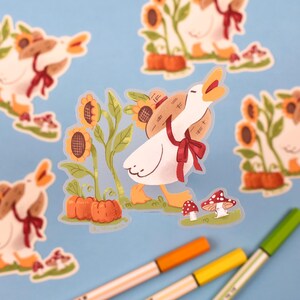 May include: A set of five stickers featuring a cartoon goose wearing a straw hat and carrying a basket of sunflowers. The goose is depicted in various poses, including walking, standing, and looking up. The stickers are printed on clear vinyl and have a glossy finish.