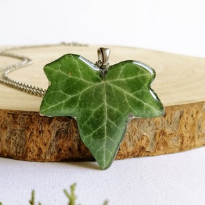 This lovely real red leaf necklace appears on a white background with another little green plant. A wonderful piece of nature in this unique handmade creation. Natural light gives it an endearing and iridescent glow. Unique handmade creation for you