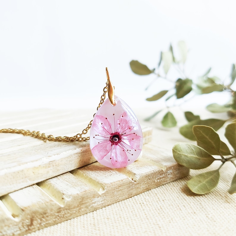 This beautiful real flower pendant appears on a luminous white background. Lovely crystalline necklace to have a piece of nature always with you. Hypoallergenic stainless steel golden chain. Magical nature inspiration in this handmade creation.