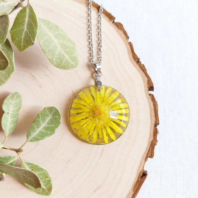 This stunning real yellow dandelion necklace appears on a luminous white background. A wonderful piece of nature in this unique handmade creation. Customizable chain length. Ask me for a round metal tag with an initial or a date or a short name.