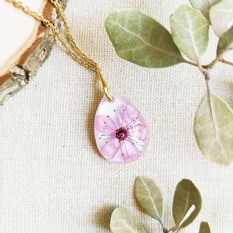 Cute and delicate real flower necklace made of crystalline resin with a real cherry flower inside. Radiant crystal-clear pendant teardrop shaped inspired by the spring. Golden hypoallergenic stainless steel chain. Unique handmade creation for you!