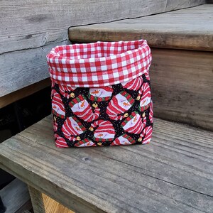 May include: A red and white gingham fabric-lined storage basket with a black and white snowman pattern.