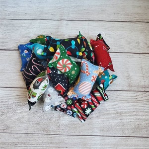 May include: A collection of 12 colorful, festive catnip toys with various holiday-themed patterns, including snowflakes, candy canes, and Christmas lights. The toys are made of soft fabric and are perfect for cats to play with.