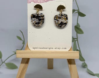 May include: Dangle earrings featuring a gold-tone semi-circle stud attached to a shield-shaped pendant with a marbled black, white, and gold foil pattern. The earrings are displayed on a white card labeled KP Bliss DESIGNS and kpblissdesigns.etsy.com.