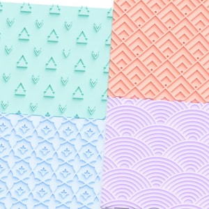 Può includere: Quattro tappetini da forno in silicone diversi con motivi in rilievo. I tappetini sono in tonalità di blu, verde, rosa e viola. I tappetini sono etichettati "cookies & charms".