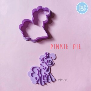 Puede incluir: Cortador de galletas de pl&aacute;stico morado con forma de Pinkie Pie de My Little Pony. El cortador est&aacute; en dos piezas, una para el contorno y otra para los detalles. El texto "Pinkie Pie" est&aacute; impreso debajo del cortador.