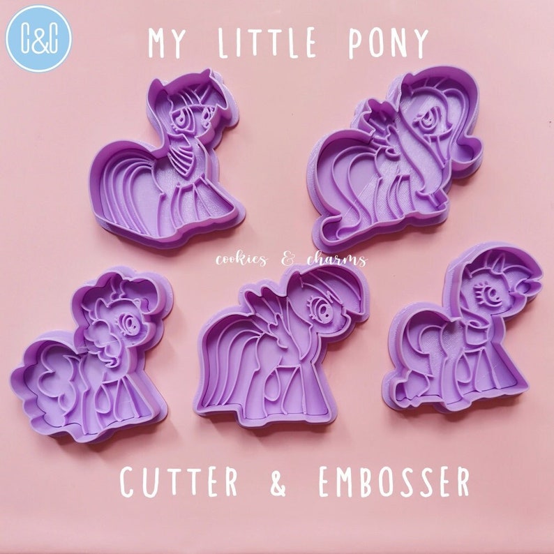Puede incluir: Conjunto de cinco cortadores de galletas y estampadores My Little Pony de pl&aacute;stico morado. Los cortadores presentan diferentes dise&ntilde;os de ponis.