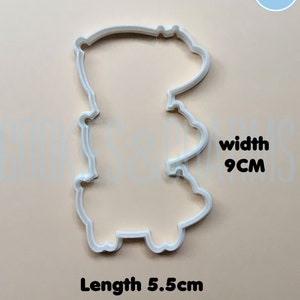 May include: White plastic cookie cutter shaped like a cartoon bear. The cutter is 5.5 inches long and 9 inches wide.