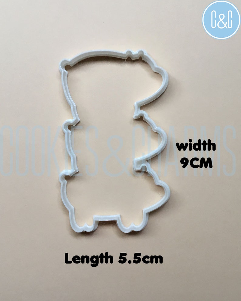 May include: White plastic cookie cutter shaped like a cartoon bear. The cutter is 5.5 inches long and 9 inches wide.