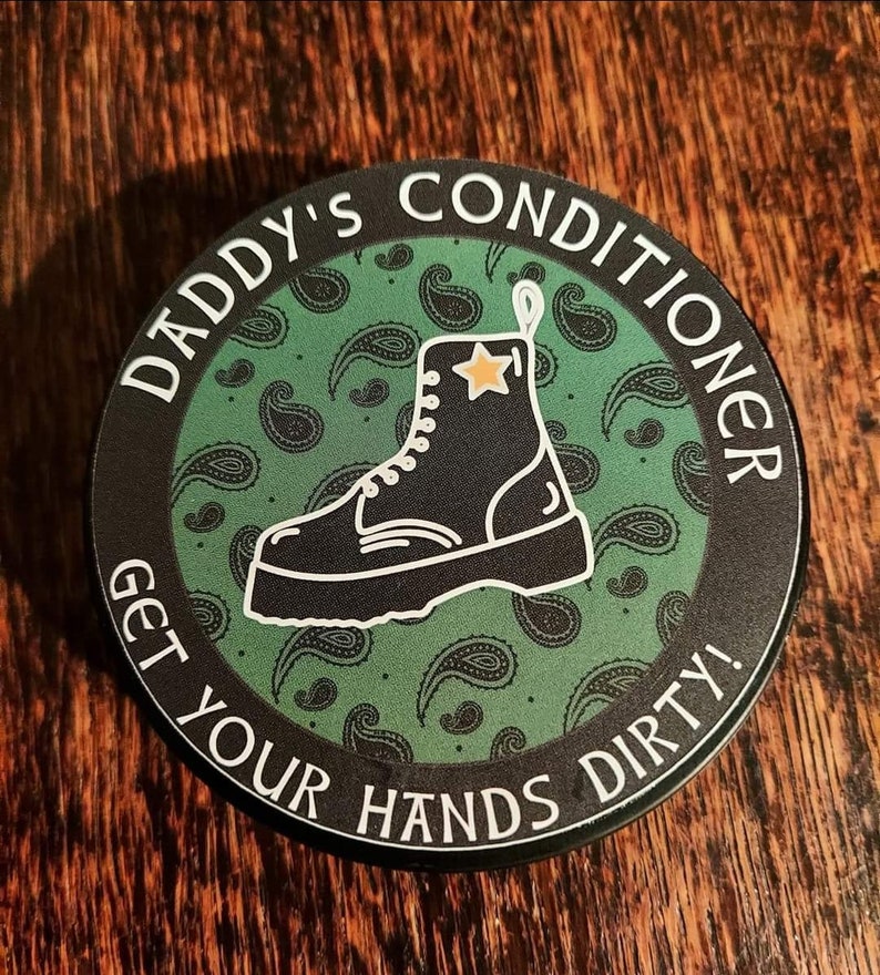 May include: A black and green round sticker with the text "Daddy's Conditioner Get Your Hands Dirty!" in white lettering. A black boot with a white star on the side is in the center of the sticker.