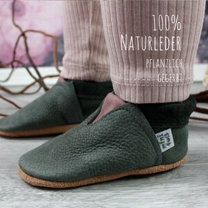 May include: A pair of dark green leather shoes with a brown sole. The shoes are made of 100% natural leather and are vegetable tanned. The shoes have a label that says "My little idea".