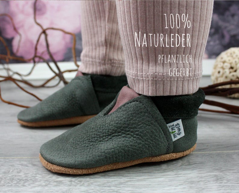 May include: A pair of dark green leather shoes with a brown sole. The shoes are made of 100% natural leather and are vegetable tanned. The shoes have a label that says "My little idea".