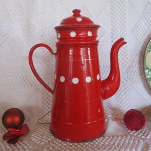 Könnte beinhalten: Rote Emaille-Kaffeekanne mit weißen Punkten und goldener Verzierung. Die Kanne hat einen Deckel und einen Ausguss.