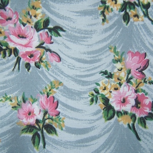 May include: A light blue fabric with a repeating pattern of pink and yellow flowers. The flowers are arranged in bouquets and have a vintage style.