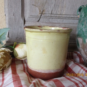 Peut inclure: Un pot en céramique jaune avec un bord brun. Le pot est posé sur une nappe à carreaux rouge et blanc.