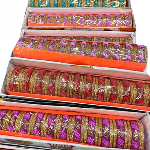 Puede incluir: Una pila de pulseras coloridas con detalles dorados. Las pulseras est&aacute;n dispuestas en cajas con tapas naranjas. Las cajas est&aacute;n etiquetadas con "Bangles Super Deal".