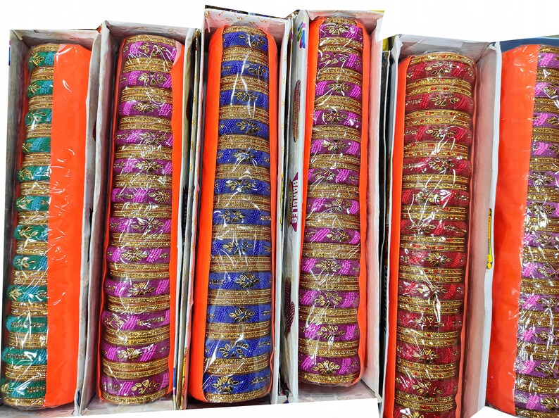 Puede incluir: Surtido de pulseras coloridas en cajas. Las pulseras son de pl&aacute;stico y tienen un borde dorado. Las cajas son de color naranja y blanco.
