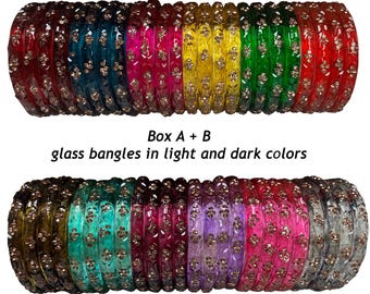 Puede incluir: Dos filas de brazaletes de vidrio en varios colores, incluyendo rojo, azul, rosa, amarillo, verde, morado y transparente. Cada brazalete presenta pequeños detalles florales metálicos incrustados. El texto "Box A + B glass bangles in light and dark colors" está centrado entre las filas.