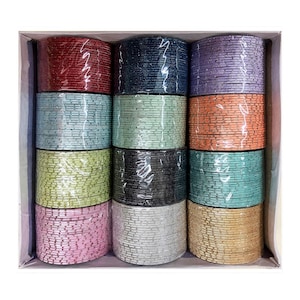 Pode incluir: Uma caixa cheia de pilhas de pulseiras coloridas. As pulseiras são embaladas em plástico transparente e vêm em várias cores, incluindo vermelho, azul, roxo, verde e dourado. As pulseiras estão cuidadosamente dispostas em fileiras dentro da caixa.