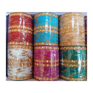 May include: A selection of vibrant bangles in shades of red, turquoise, gold, white, pink, and green. The bangles are arranged in stacks and encased in clear plastic. The bangles are decorated with gold-coloured detailing.