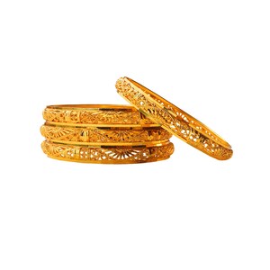 May include: A stack of four gold bangles with intricate openwork designs, alongside a fifth bangle. The bangles are a bright, shiny gold color, and the openwork creates a delicate, lacy pattern. The jewelry is set against a white background.