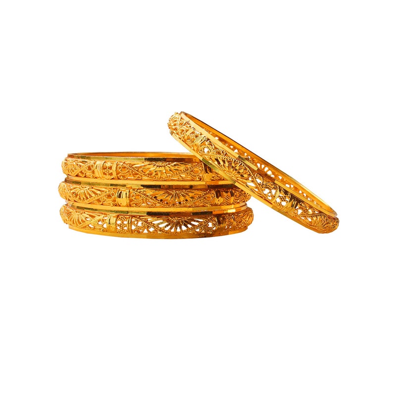 May include: A stack of four gold bangles with intricate openwork designs, alongside a fifth bangle. The bangles are a bright, shiny gold color, and the openwork creates a delicate, lacy pattern. The jewelry is set against a white background.
