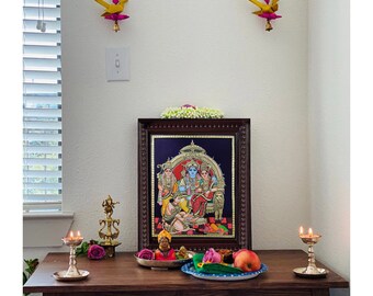 Pode incluir: Uma pintura religiosa emoldurada com detalhes dourados e uma moldura de madeira escura é exibida em uma mesa de madeira. Duas pequenas lâmpadas de latão com velas acesas ladeiam a pintura. Há objetos decorativos.