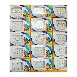 May include: A selection of Jeevika brand bindi packs. Each pack contains an assortment of colourful, decorative face gems in various shapes and sizes. The packaging features a peacock design and the words "Fancy Work".