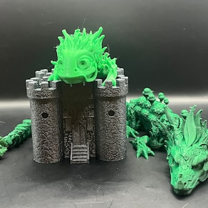 Puede incluir: Una figura de dragón verde impresa en 3D con un castillo en la espalda. El dragón tiene una cabeza puntiaguda y una cola larga. El castillo tiene una torre y una puerta.