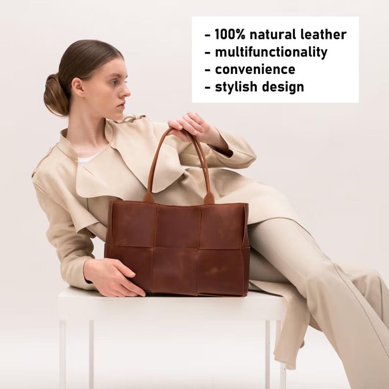 May include: A brown leather tote bag with a woven design. The bag is being held by a person wearing a beige coat and pants. The text on the image reads: - 100% natural leather - multifunctionality - convenience - stylish design