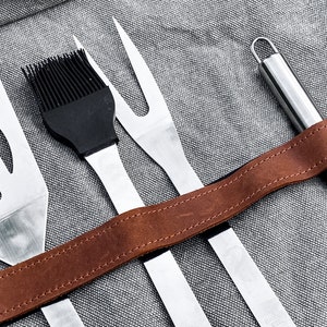 以下が含まれることがあります： 茶色の革ひもが付いた4つのグリル用具のセット。道具には、ヘラ、塗りブラシ、フォーク、ナイフが含まれています。