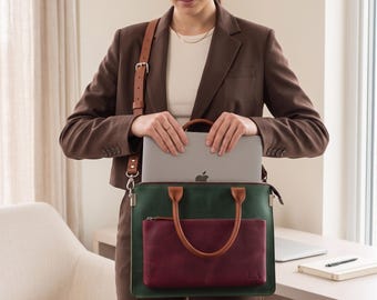 May include: A rectangular dark green laptop bag with a maroon front pocket and brown leather handles. The bag features a detachable brown shoulder strap with a silver buckle and the embossed initials EA on the lower right corner.