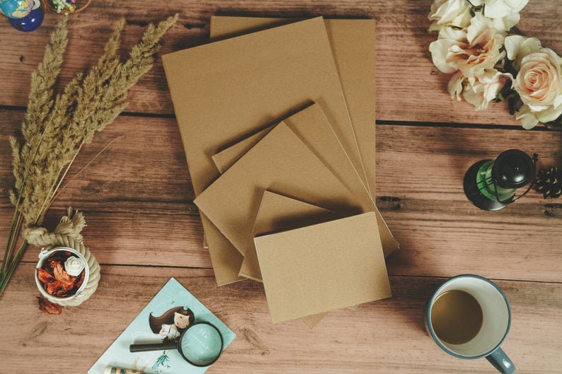 Puede incluir: Un conjunto de cinco cuadernos de papel marr&oacute;n de diferentes tama&ntilde;os apilados sobre una superficie de madera. Los cuadernos est&aacute;n hechos de papel reciclado y tienen un aspecto natural y r&uacute;stico.