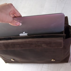 May include: A brown leather messenger bag with a laptop inside. The bag has a flap closure and a shoulder strap.