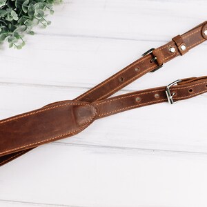 Peut inclure: Une sangle de cam&eacute;ra en cuir marron avec deux boucles r&eacute;glables et un anneau m&eacute;tallique. La sangle est con&ccedil;ue pour porter un appareil photo autour du cou ou de l'&eacute;paule.