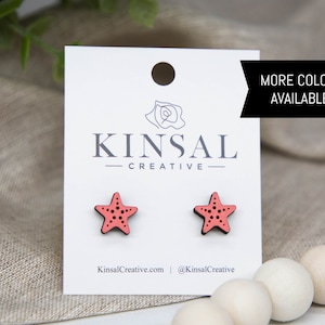May include: A pair of pink wooden starfish earrings on a white card with the text "Kinsal Creative" and "More Colors Available!"