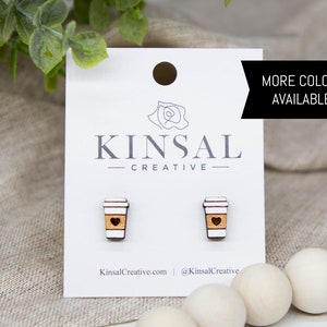 May include: A pair of wooden coffee cup earrings with a heart design. The earrings are on a white card with the text "Kinsal Creative" and "KinsalCreative.com | @KinsalCreative". The text "MORE COLORS AVAILABLE!" is in the top right corner of the card.