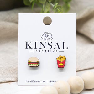 May include: Wooden stud earrings featuring a hamburger and a container of fries. The earrings are on a white card with the text "KINSAL CREATIVE" and the website KinsalCreative.com.