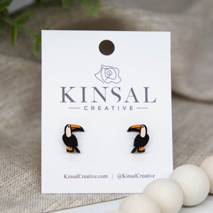 May include: A pair of toucan stud earrings on a white card with the text "Kinsal Creative".