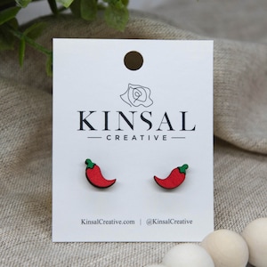 May include: A pair of red chili pepper earrings on a white card with the text "Kinsal Creative".