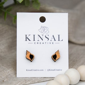 May include: A pair of wooden shell stud earrings on a white card with the text "Kinsal Creative".