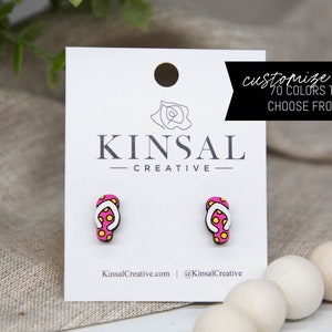 May include: Pink and yellow polka dot flip flop earrings. The earrings are made of wood and have a white strap. The earrings are on a white card with the text "Kinsal Creative" and "Customize me 70 colors to choose from!"