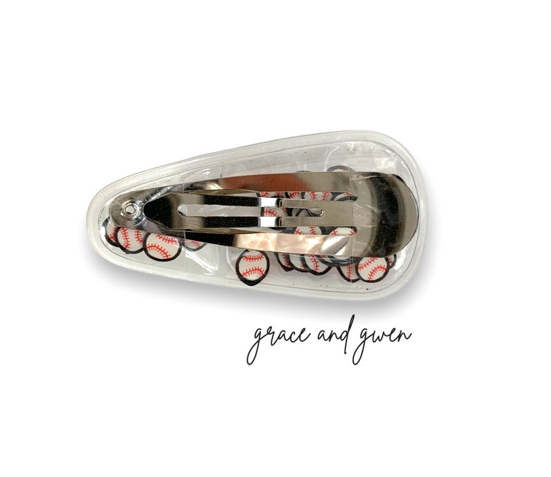 May include: A clear plastic hair clip with a silver metal clasp. The clip is filled with small baseball-themed images.