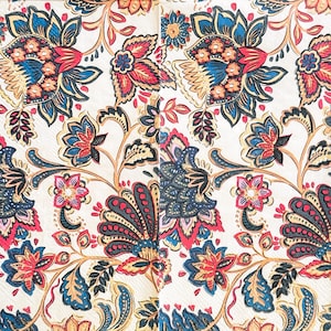 Peut inclure: Une serviette en papier présentant un motif floral répétitif sur un fond crème. Le design comprend des fleurs et des feuilles stylisées dans des tons de bleu profond, de rouge vif et d'orange doux, avec des contours noirs définissant chaque élément.