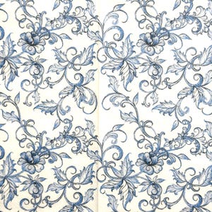 May include: A white paper surface featuring a repeating pattern of blue floral motifs and intricate swirling vines. The design consists of detailed blossoms and pointed leaves rendered in varying shades of blue, creating a continuous botanical print.