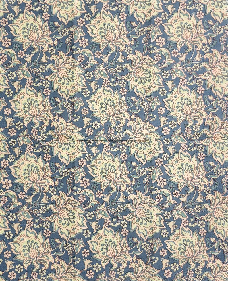 May include: A fabric with a repeating floral pattern. The design features large, stylized flowers in cream, light green, and pink, set against a deep blue background. Smaller white flowers and vines fill the spaces between the larger blooms.