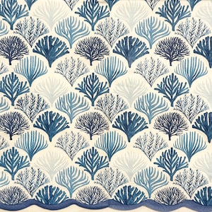 Puede incluir: Un patrón repetido de corales y algas estilizados en tonos azules y blancos sobre un fondo blanquecino. El diseño presenta corales en forma de abanico y delicadas frondas de algas marinas. Un borde azul ondulado enmarca el borde inferior.